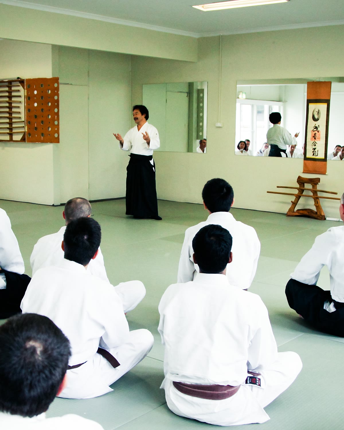 Students seated on the mat as Takayasu Sensei speaks to the class