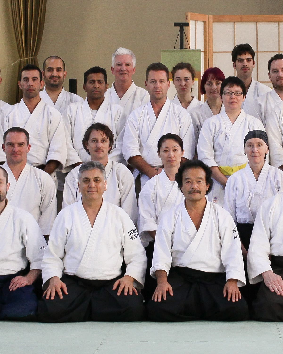 Members of the Takemusu Aiki Association seated on the mat before a shoji screen