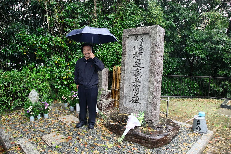 Takayasu Sensei in front of O-Sensei's memorial stone