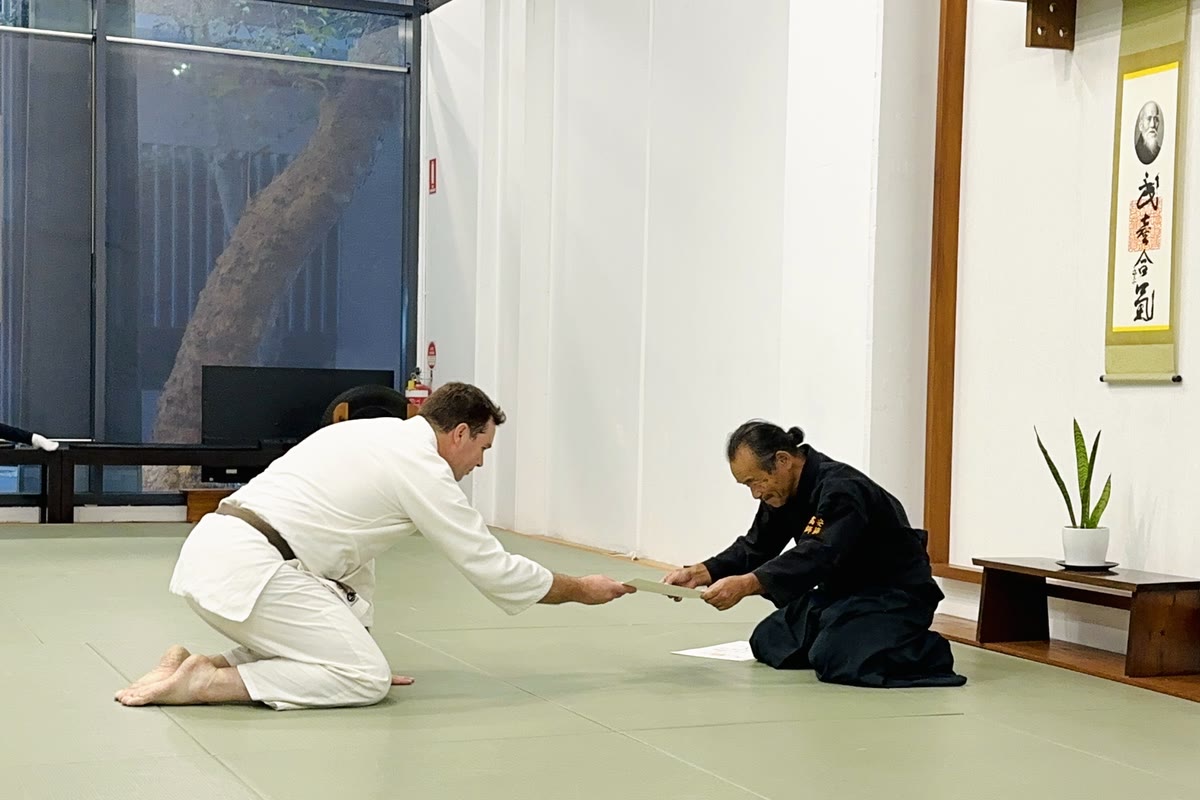 A student in seiza receiving his certificate from Takayasu Sensei